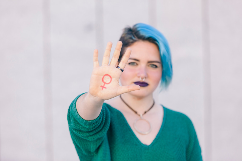 feminist showing a symbol of feminism on her hand